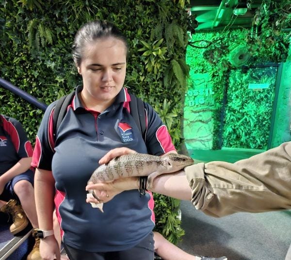 Student patting a lizard during excursion to zoo